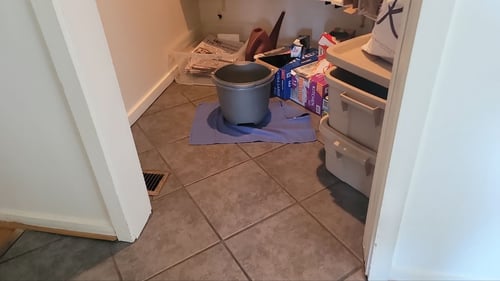 bucket catching water in a pantry caused by a roof leak