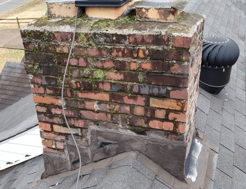 chimney with moss and vegetation growing out of mortar