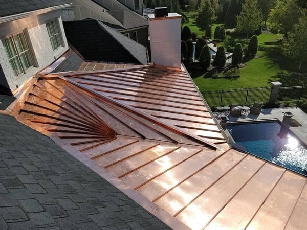 copper standing seam metal roof over back porch on a luxury asphalt shingle roof