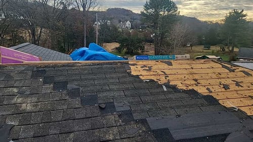 two layers of asphalt shingles being torn off before roof replacement