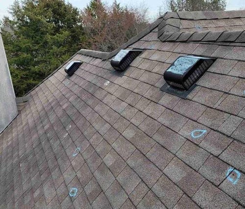 chalk marks on roof showing hail damage to asphalt shingles and roof vents