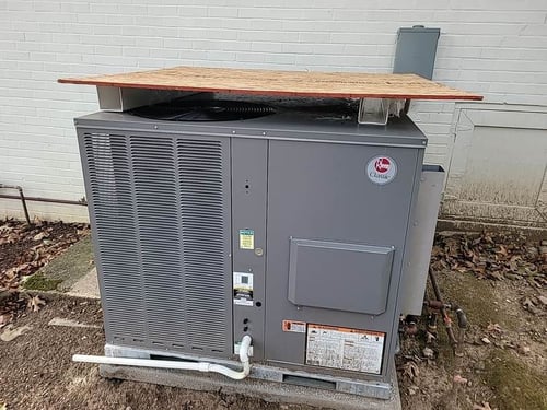 wooden board over HVAC unit to protect it during a roof replacement
