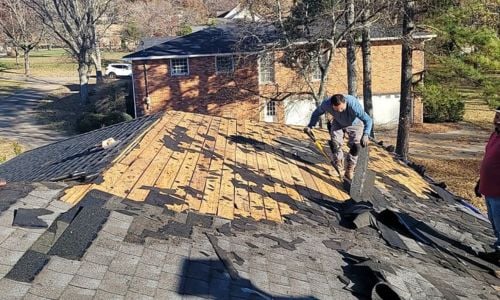 tearing off an old asphalt shingle roof during a roof replacement
