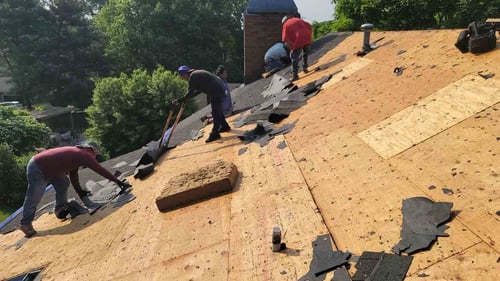 old asphalt shingle roof being torn off down to the decking