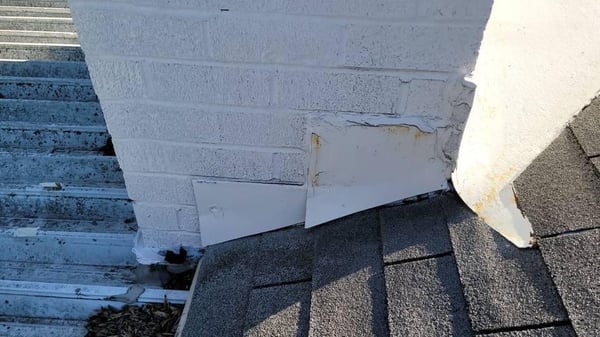 rusted and cracked flashing around a brick chimney