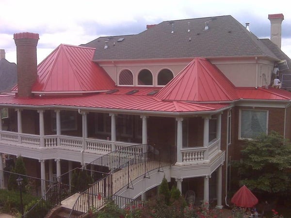 red standing seam metal roof over a back porch on an asphalt shingle roof