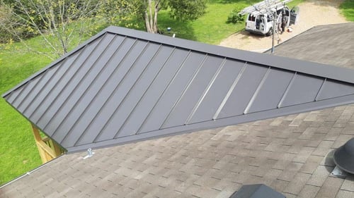 standing seam metal roof over a front porch on an asphalt roof