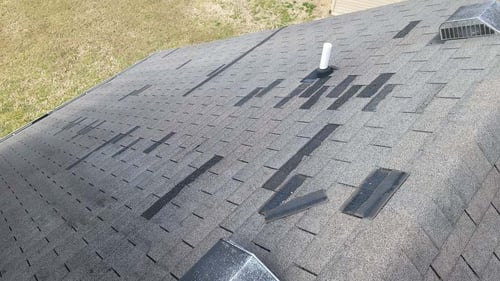 missing asphalt shingles from wind damage to a roof