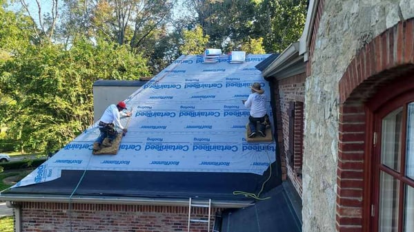 roofers tied off on steep roof pitch